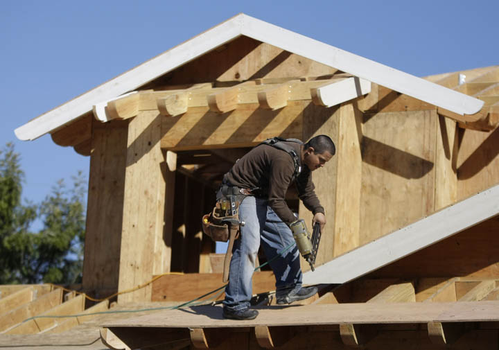 A carpenter works on the roof of a new home recently in Palo Alto, Calif. Builders of new homes are struggling to compete in markets saturated foreclosures.