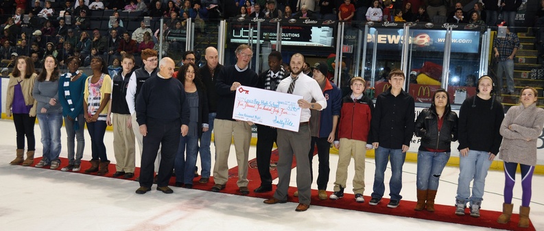 Zachary Davis, right, vice president of ticket sales for the Portland Pirates, presents a $5,425 check to Casco Bay High School Principal Derek Pierce between periods of Saturday’s game between the Pirates and Providence Bruins. Students from Casco Bay High’s Junior Achievement Program created a logo, developed a business plan and finalized a mission statement and vision for the game.