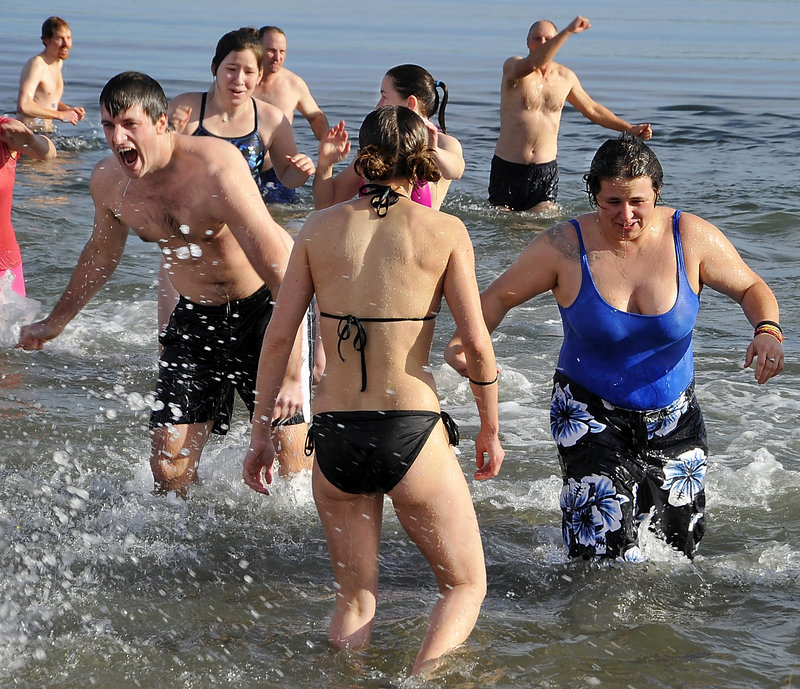 Participants react to the cold water as about 40 people take the Natural Resources Council of Maine-sponsored Polar Plunge at East End Beach on Friday.