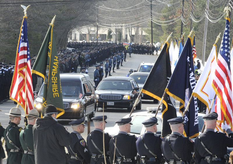 The Associated Press The funeral procession for John Maguire, a Woburn, Mass., police officer, heads toward the Shriners Auditorium on Friday in Wilmington, Mass. Maguire was shot after responding to an armed robbery attempt and later died of his wounds. Maguire, 60, was a 34-year veteran of the department and the son of the citys former police chief.