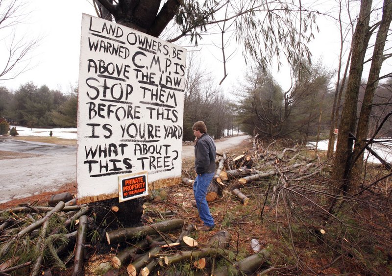 Michael Breton walks past a sign he put up last March after a crew hired by CMP felled trees on his property off Falmouth Road in Windham. Under PUC rules, CMP needs to provide direct notice at least 30 days before trimming.
