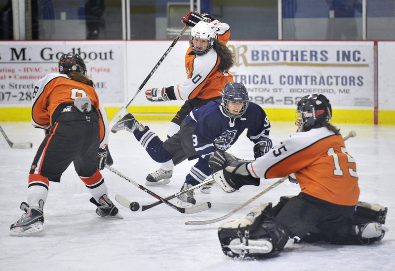 Portland's McKinzie Parker gets tripped up by the Biddeford defense but still gets a shot off on goalie Emily Brassley on Monday at Biddeford Ice Arena. The Bulldogs suited up just 12 players because of injuries.