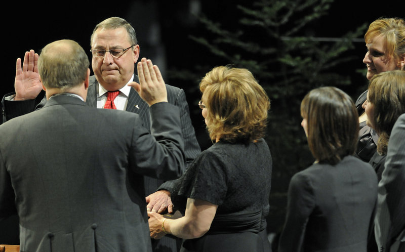 Paul LePage takes the oaths of office at the Augusta Civic Center Wednesday as his wife holds a family Bible.