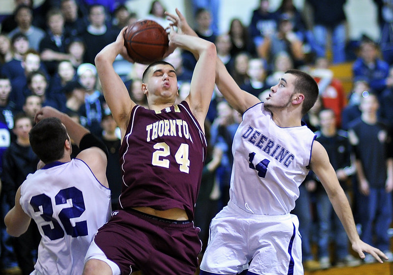 Andrew Shaw of Thornton Academy grasps a rebound between Jamie Ross, left, and Jackson Frye of Deering during Deering’s 50-48 victory Friday night. The SMAA rivals will meet just once in the regular season this year.