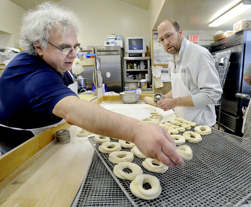 Rick Fournier, left, owner of Tony's Donuts, shows Ray Routhier how to cut doughnuts.