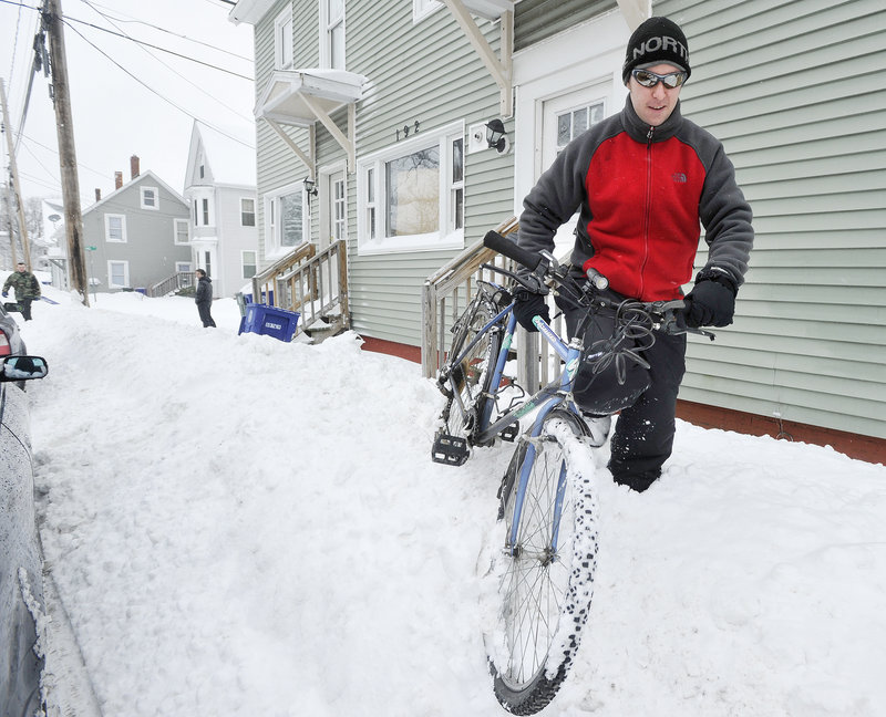 Terrance Cushman braves any weather in commuting from Westbrook to his job in South Portland. Here he pushes his bike through a snowbank in front of his Brown Street home, embarking on a 5 1/2 mile trip to work.