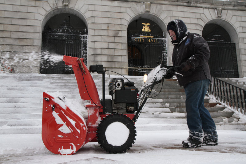 City employee Henry Fontaine clears snow from the steps of Portland City Hall on Wednesday.