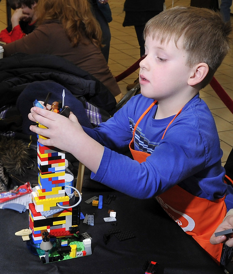 Tommy Whytock, 5, of Scarborough puts a top floor capsule on a LEGO house he was helping to build.