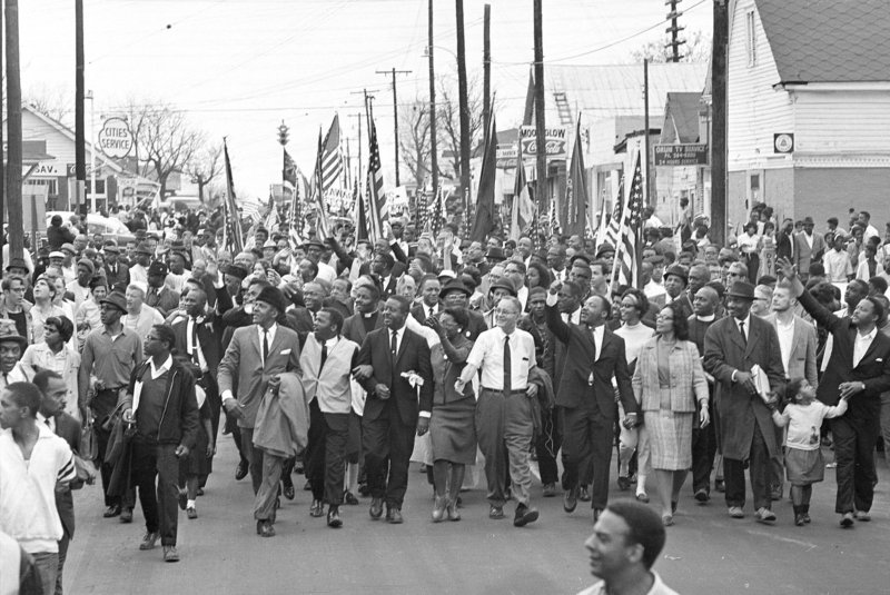 Dr. Martin Luther King Jr., fourth from right, waves as marchers set out on the first day of a five-day, 50-mile march to the state capital at Montgomery, Ala., on March 21, 1965.
