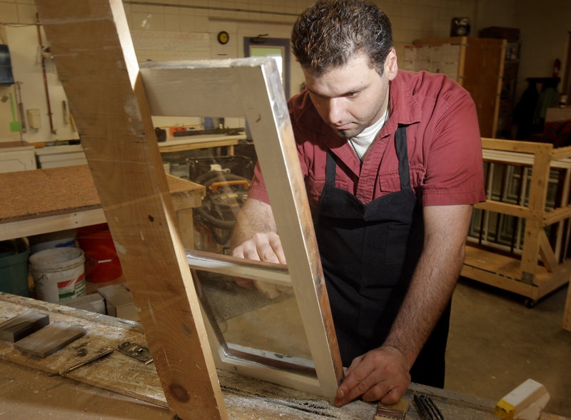 Navid Ahadzadeh cleans a window at Bagala Window Works in Falmouth. Owner Marc Bagala will conduct a series of window restoration workshops beginning in February. Below: Frames being restored at Bagala Window Works.