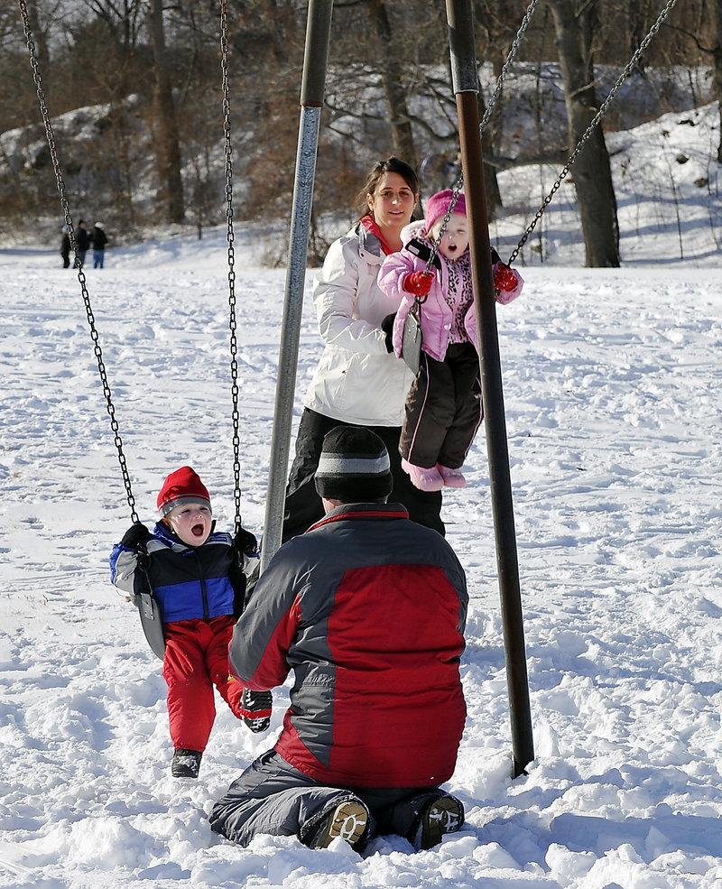 Matt Marks and his wife, Sandi Story, of South Portland take a break from sledding to push Aidan, 2, and Abby, 4, on the swings at Fort Williams.