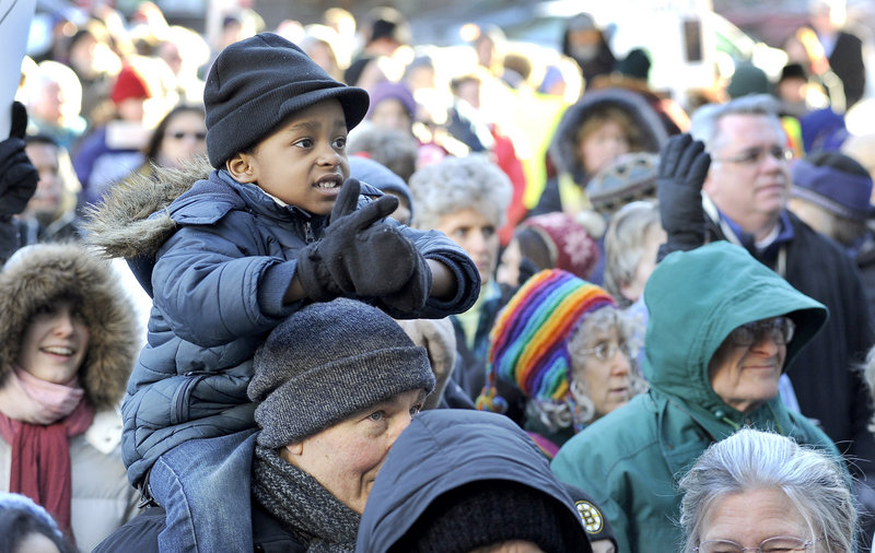 Three-year-old Dmitri O’Sullivan is perched atop the shoulders of Bob Bahm from Falmouth as they listen to speeches at Portland City Hall during the Martin Luther King Jr. Day march and rally for justice in Portland on Monday.