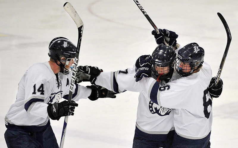 Colin Merrill, center, is congratulated by Zach Luce, right, and Anthony Bowden after scoring in the first period Monday against Cheverus. Portland improved to 6-5 with a 4-1 victory.