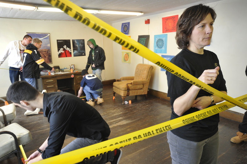 Deering High School students scour a manufactured crime scene as part of a “CSI”-style forensics science course that was begun by teacher Karen Shibles, right. In the photo, students are taking measurements for data that will be used to re-create and possibly solve the crime. The course, first offered in 2009, has become very popular.