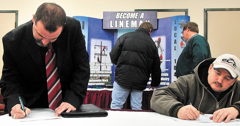 Mark Fournier of Sabbatus, left, and Leo Perreault of Milan, N.H., complete work applications Tuesday in front of the IBEW Local 104 booth at the job fair in Augusta.