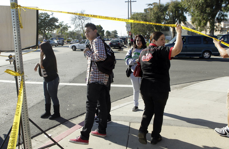 Alma Aguas, right, walks through yellow tape Tuesday on the way to pick up her 15-year-old son at Gardena High School in Gardena, Calif., following reports of a number of students being wounded during a shooting.
