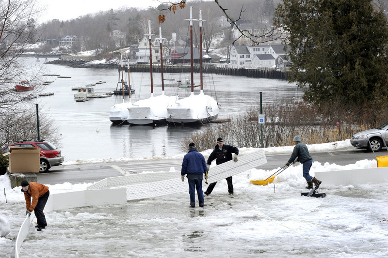 Community volunteers put up the sideboards and clear snow while building an ice rink from a kit in Camden Harbor Park on Jan. 19. The rink is located next to the town library and opened for free public use last week.