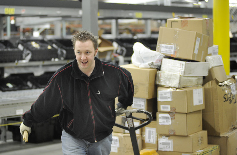 Kevin Kennie moves boxes at the Olympia Sports distribution center in Westbrook. The company employs about 2,000 people throughout the Northeast.