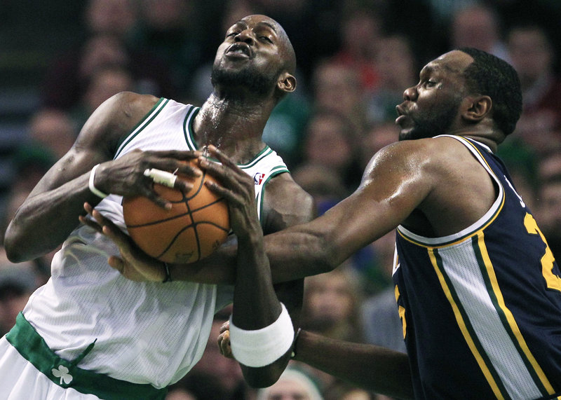 Al Jefferson, right, of the Utah Jazz reaches in and fouls Kevin Garnett on a drive Friday night at Boston. Garnett had a team-high 21 points in the Celtics’ 110-86 win.