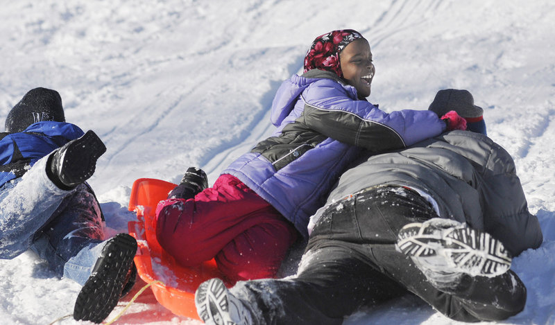 Fatuma Mohamed, 8, laughs as she crashes on a sled with her brothers Hassan Mohamed, 11, left, and Abdi Mohamed 16, of Portland during the WinterKids event to introduce immigrant and refugee families to winter activities Saturday. The Mohamed family is originally from Kenya.
