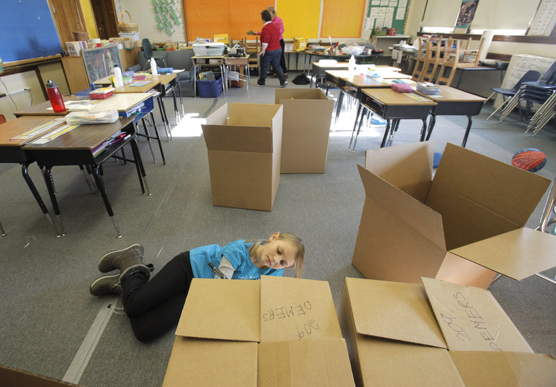 Maddie Kerr, a third-grader at Nathan Clifford School, writes her teacher’s name on a cardboard carton in her classroom on Saturday. Students, teachers and parents boxed up items in preparation for the move to Ocean Avenue School.