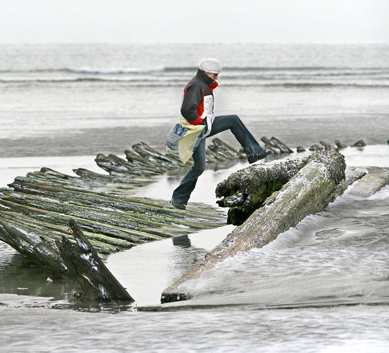 Gaella Materne of Portland walks on the remains of the schooner Howard W. Middleton, which sank in 1897, as she picks up trash during the Surfrider Maine Higgins Beach cleanup.