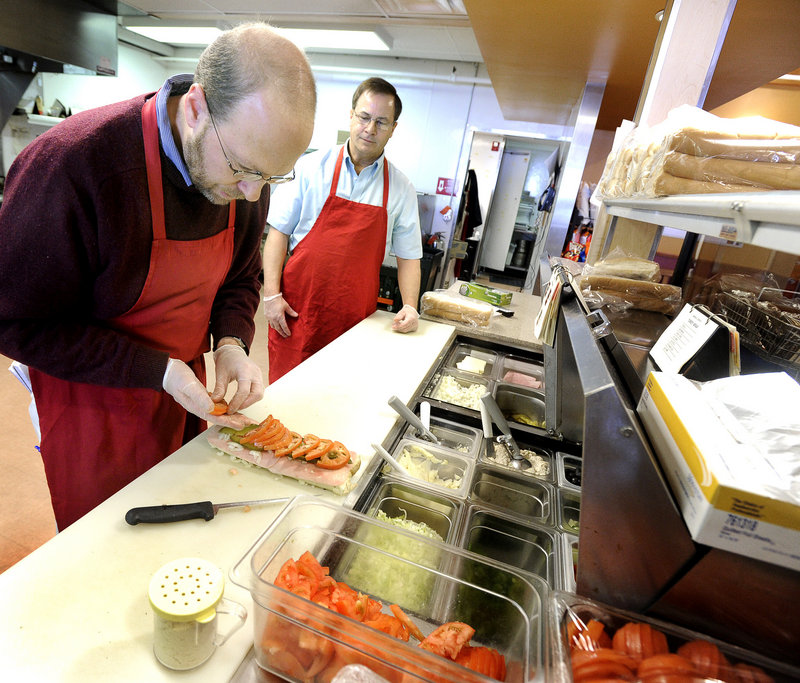 Steve Shea, right, director of operations for Amato's in Freeport, guides Ray Routhier.