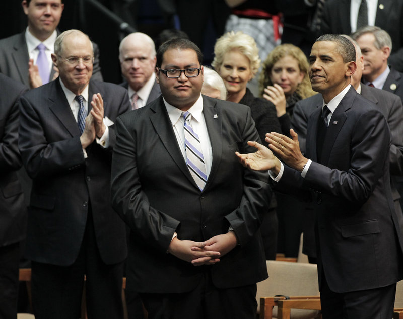 President Barack Obama, right, applauds Daniel Hernandez, center.