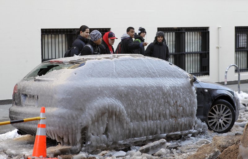 Pedestrians gawk at a car that was covered in ice after a water pipe broke Monday in New York. The city doubled the number of vans checking on homeless people due to the extreme cold.