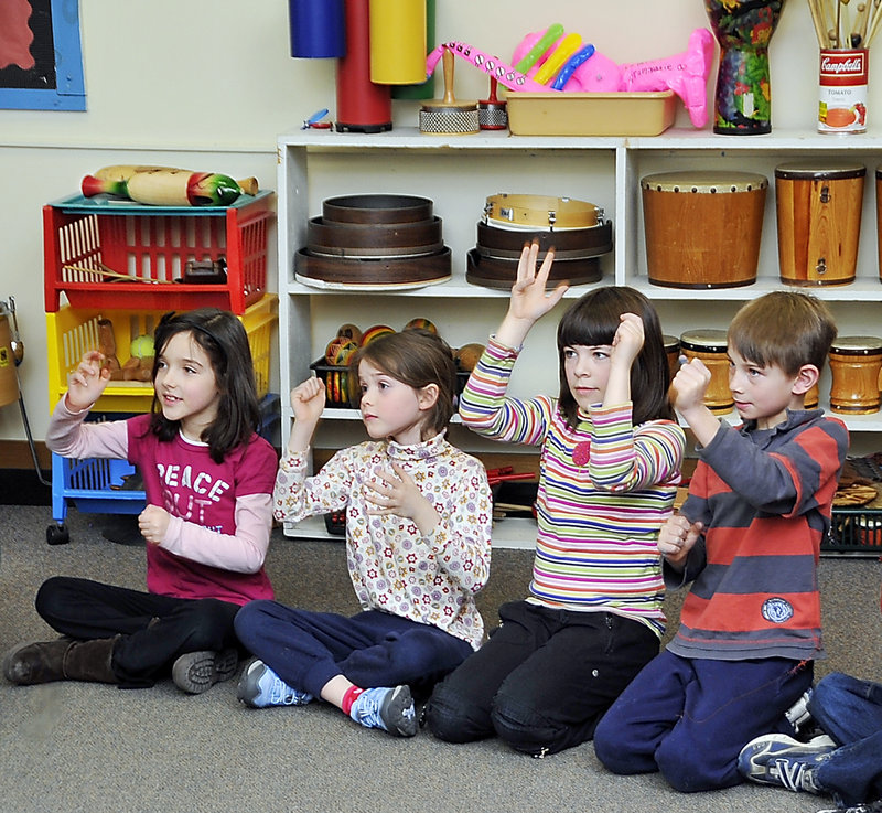 Longfellow Elementary students Ashlyn Lowe, left, Fiona Larsson, Glynis O’Meara and Jack Lagrange learn to sing different parts of a choral work by using hand signs to distinguish each part.