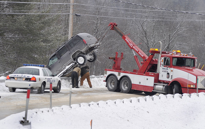 A wrecker operator removes a vehicle from a guardrail along Route 114 in Gorham on Tuesday. Early in the day, precipitation iced up on many roadways in Greater Portland, wreaking havoc with the morning commute.
