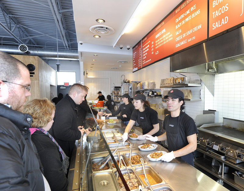 Danny Leon, on right, and Julia Calder, center, serve customers at the Chipotle Mexican Grill, a chain restaurant in South Portland.