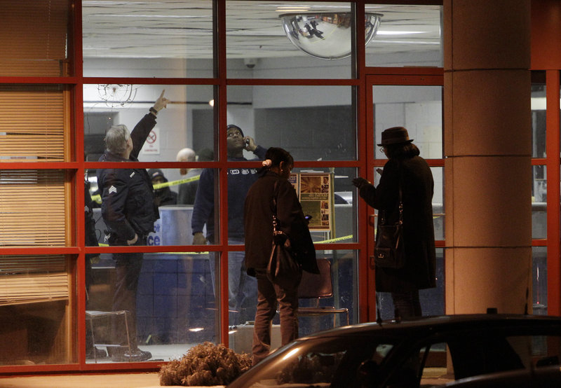 Detroit police officers inspect the scene inside and outside the Precinct 6 building in northwest Detroit, where a gunman walked into the police station and opened fire, wounding three officers on Sunday. The gunman was killed as the police returned fire.