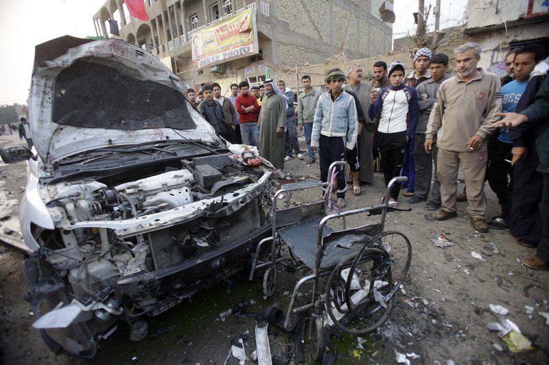 Residents of the Shula neighborhood of Baghdad stand near a destroyed car and wheelchair after Thursday’s attack. Violence in the past week has mainly targeted Shiites and security forces.