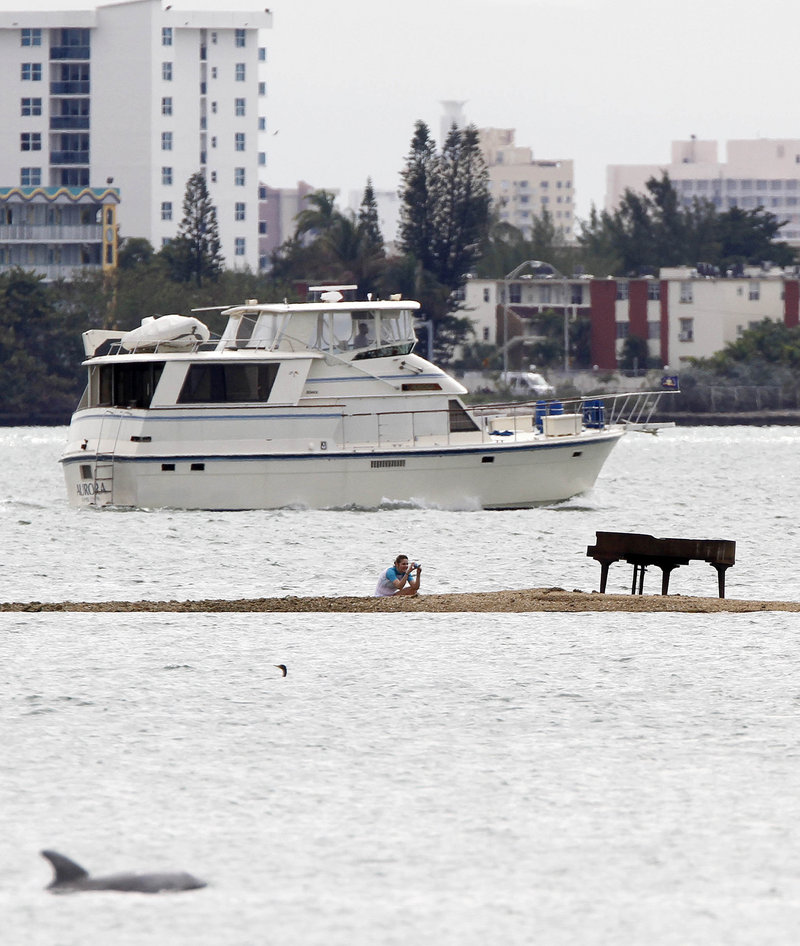 Freelance photographer Karla Murray of New York photographs a grand piano that appeared on a sandbar in Biscayne Bay, Miami. The piano was placed at the highest point of the sandbar so that it’s not underwater during high tide.