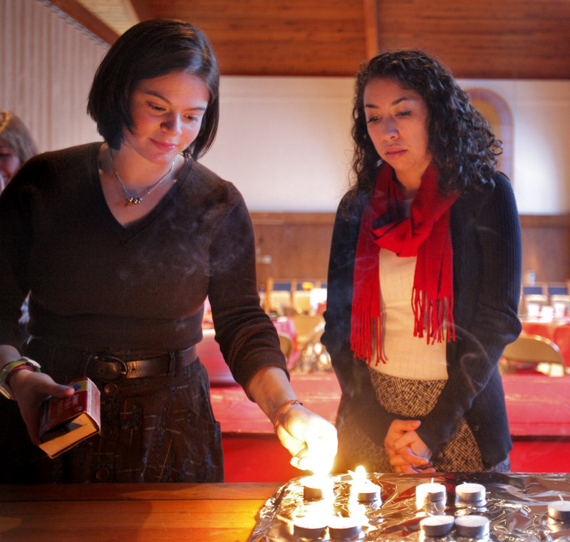 Bowdoin students Lydia Singerman, left, and Shoshana Cohn, light candles before the service.