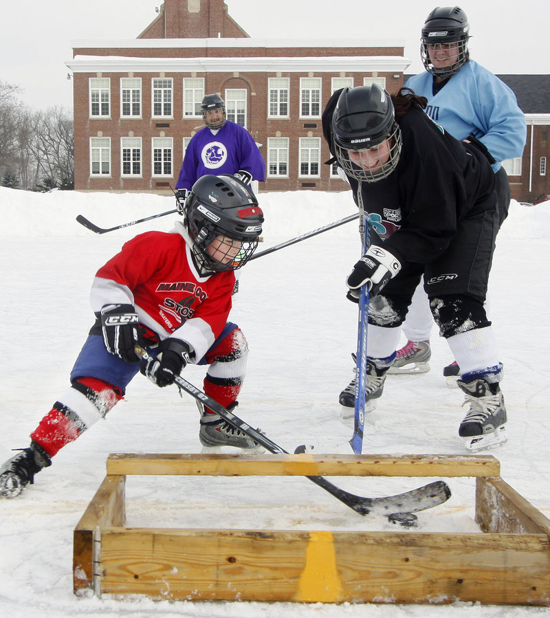 Levi Guay, 7, of Sabattus scores against Melissa Bourgoin of Lewiston during the 3-on-3 Pond Hockey Tournment at the Walton School. The tournament drew eight teams – all adults, except for Levi – and raised funds for the Auburn Youth Hockey League.