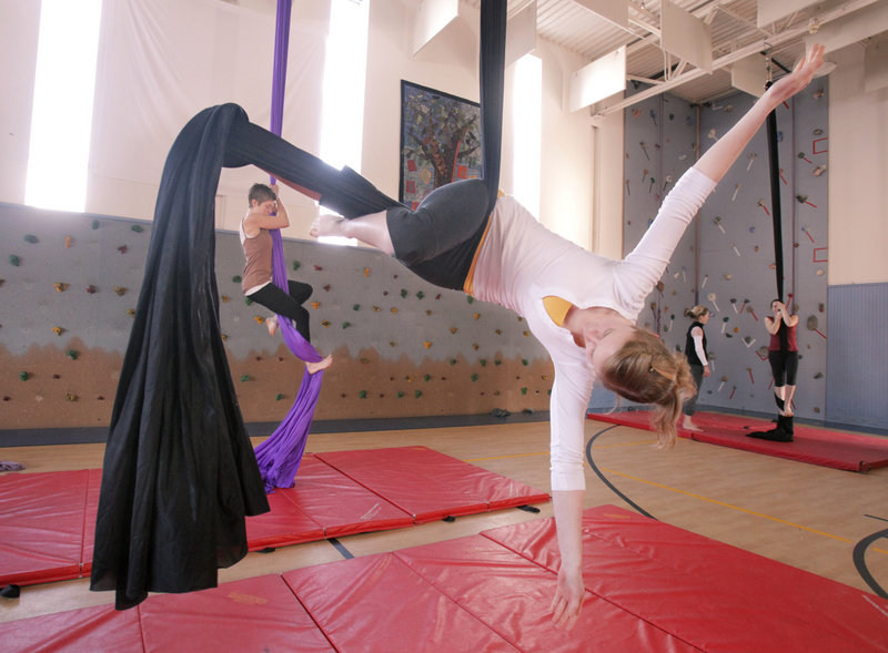 Casey Turner of Portland balances with her legs wrapped in an aerial fabric during a workshop at the Breakwater School in Portland on Saturday. Participants could learn skills on aerial fabric and also circling trapezes. In the background, Jane Frederick of Portland climbs an aerial fabric.