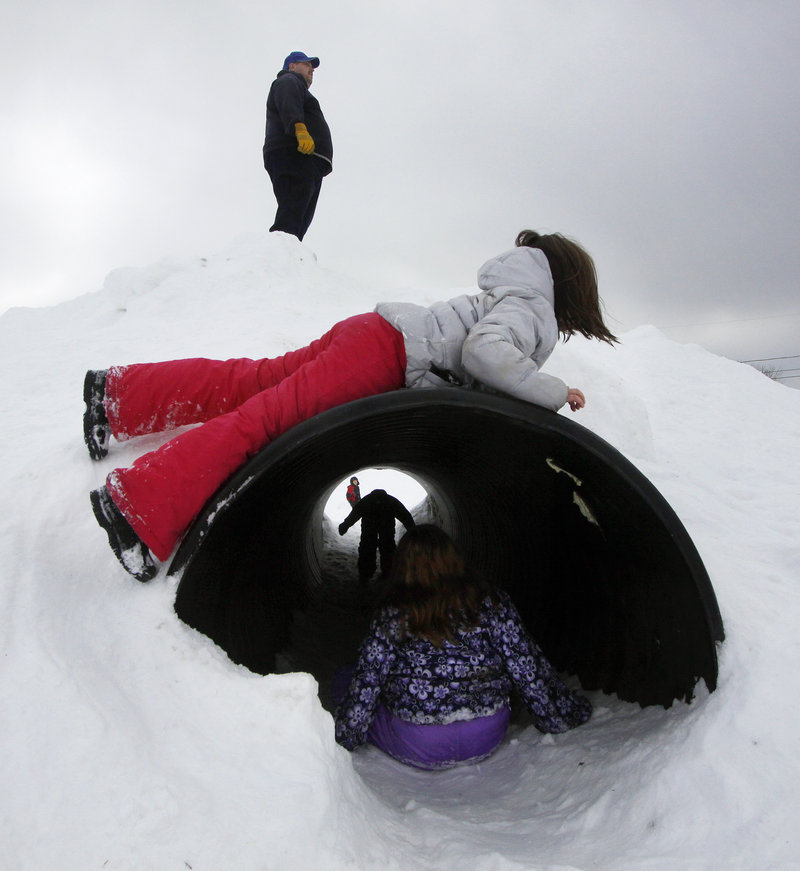 Children make the most of a culvert at the winter playground set up at Walton Field in Auburn.