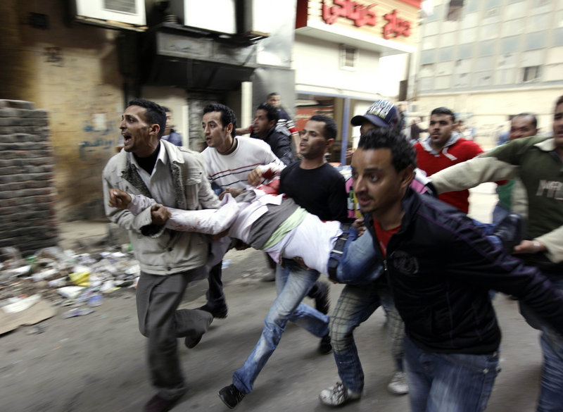 Egyptians carry an injured protester after clashing with police in Cairo on Saturday.