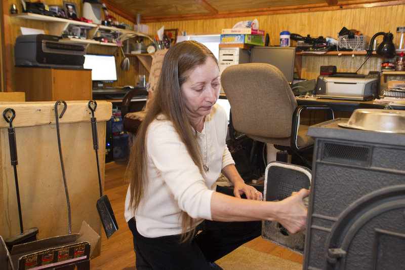 Valerie Houde fills her wood stove while waiting for a dial-up Internet connection in East Burke, Vt. "These companies, they don't care about these little pockets of places," she says.