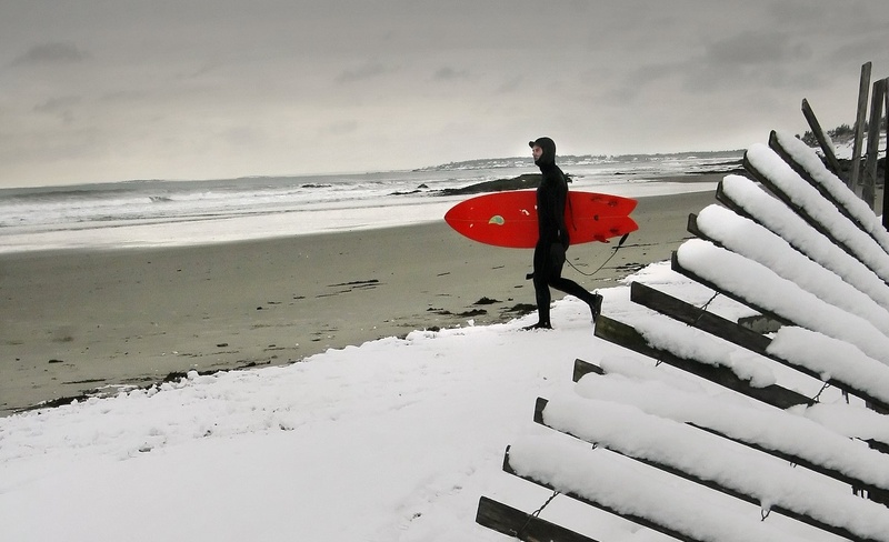 A winter surfer heads toward the ocean at Higgins Beach in Scarborough.