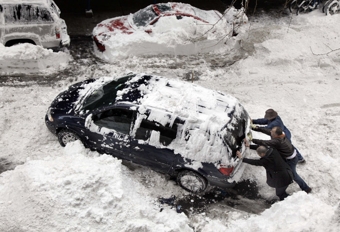 Three men attempt to free an automobile from the snow on New York's Upper West Side today.