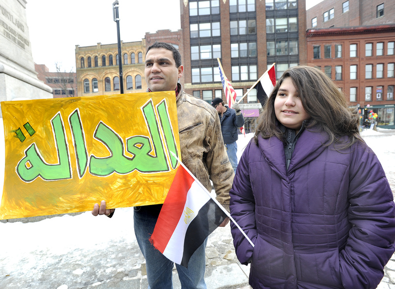 Egyptian Mody Botros, who lives in Bridgton, and his 12-year-old daughter, Amanda, attended a rally in Monument Square on Saturday in support of democracy in Egypt. Botros' sign says justice in Arabic.