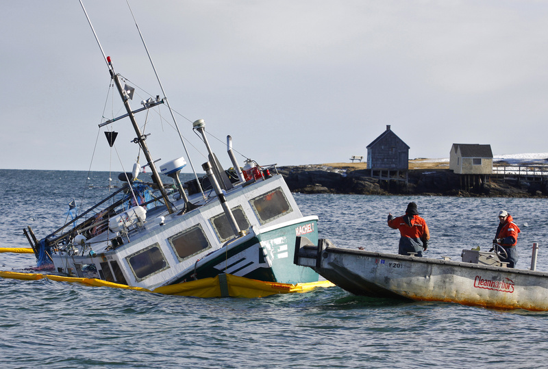 A team from Clean Harbors secures a boom around the Rachel T, a fishing vessel that ran aground near the Portland Head Light on Saturday, The boat’s owner, Terry Alexander, who was not aboard, said he had 10,000 pounds of fish in the hold.