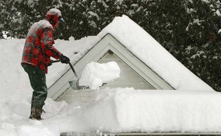 In this Feb. 2 photo, Harry Eastman shovels the snow off his garage roof in Barre, Vt. Doctors across the Northeast are seeing a spike in strained muscles from shoveling snow, broken bones from slick stairs and sidewalks, and dangerously low blood banks as fewer people venture out.