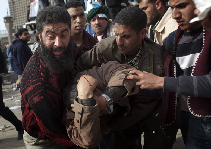 An anti-government protester gets assistance after being wounded during clashes in Cairo today