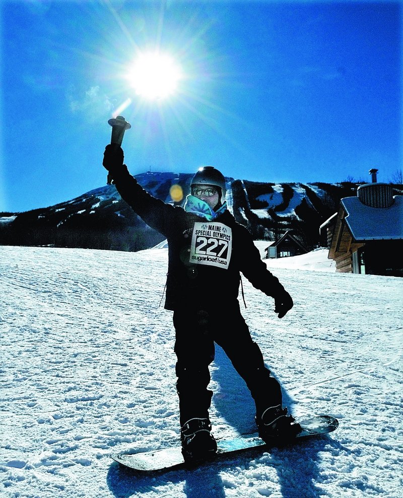 Snowboarder Keith Draper of Greene carries the Olympic torch during the opening cermony at Sugarloaf on Monday.