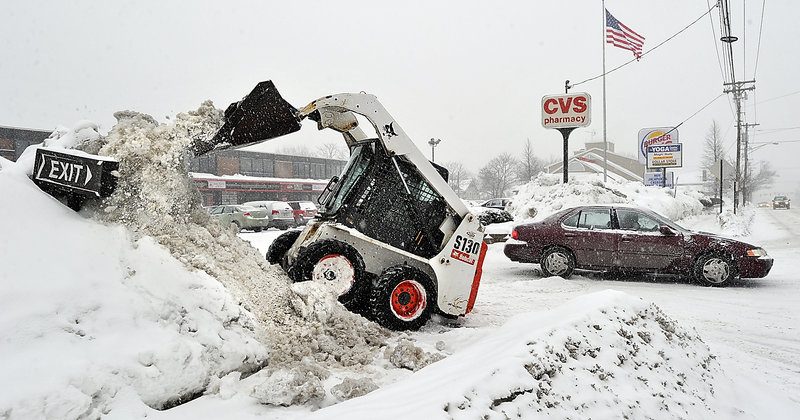 Stuart Collins, property manager for Forest Avenue Plaza, uses a Bobcat tractor to hack away at the growing snowbanks along the plaza’s access points Tuesday in advance of the latest blast of wintry weather.