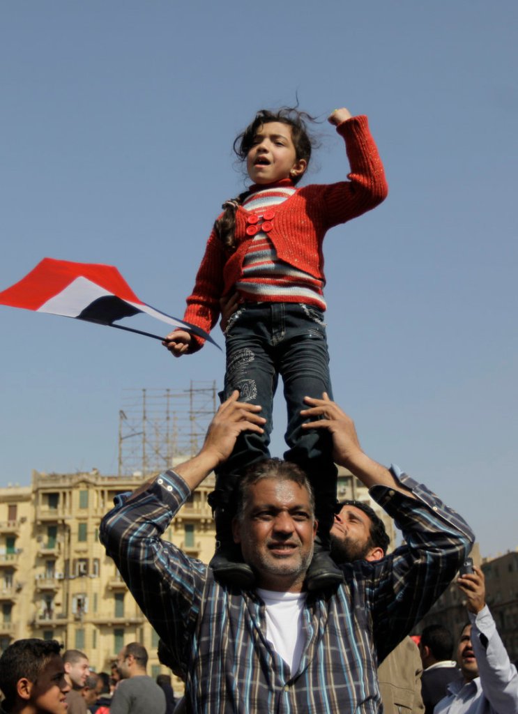A girl stands tall, pumping her fist in celebration in Tahrir Square.